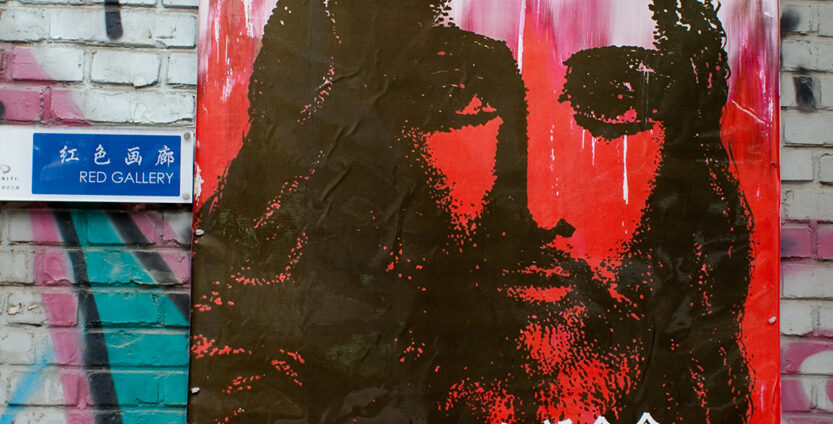 Poster hanging on a brick wall full of graffiti. Poster depicts Jesus in a graffiti style with a caption in Chinese and English- "A new command I give you- Love one another."