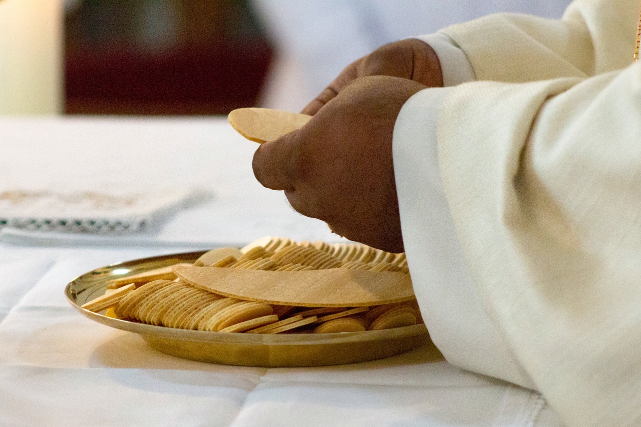 Photo of a black celebrant's hands breaking the communion wafer.