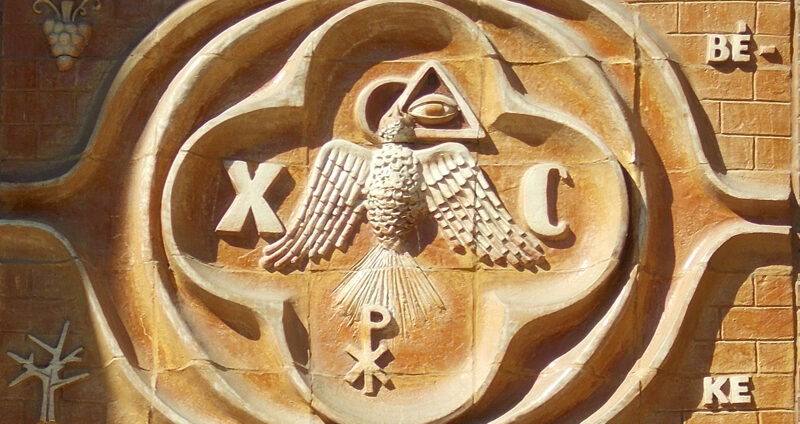 Wall carving with Eastern European symbols depicting the Eye of Providence and the Dove of Peace.